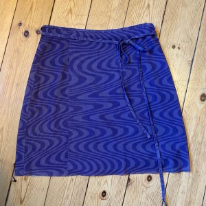 Lila omlott-kjol - Mönstrad lila tjol som knyts omlott, så går att anpassa helt efter storlek. Använd någon enstaka gång så i fint skick💗lappen är däremot bortklippt så vet ej märke