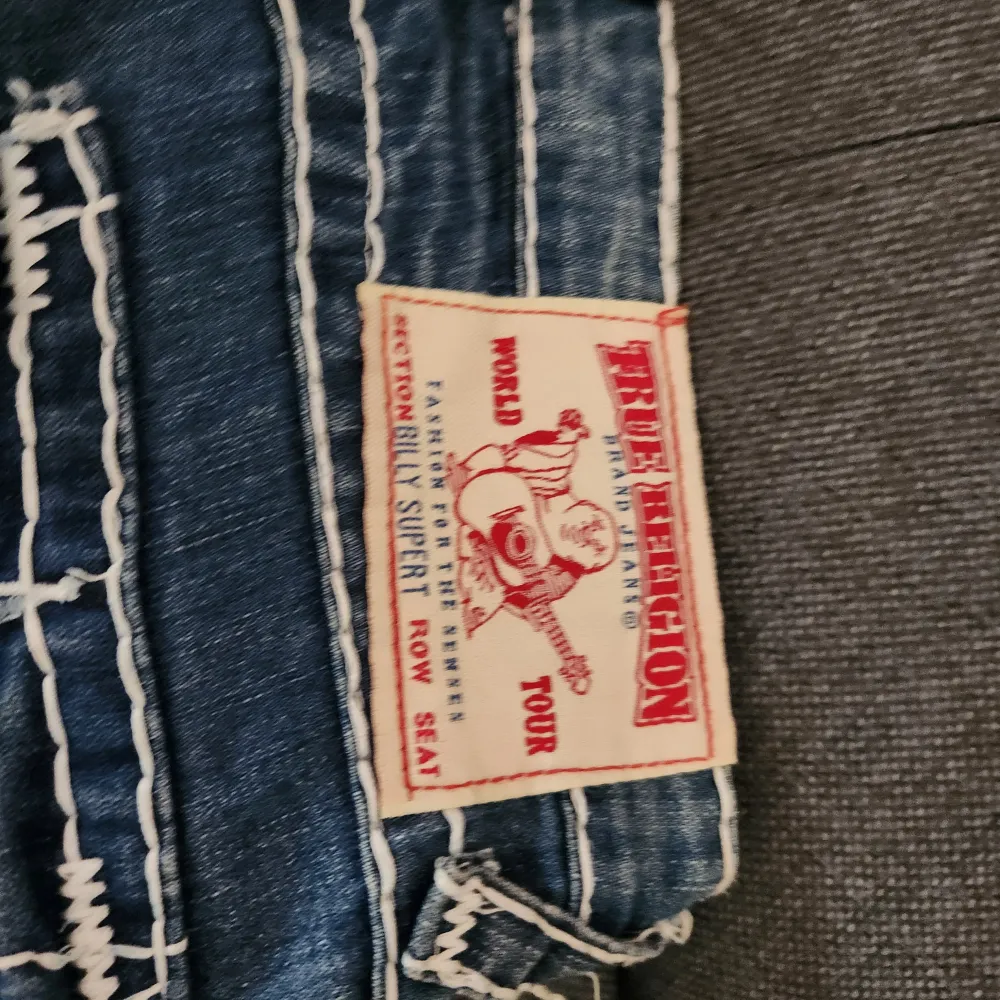 Säljer ett par snygga blå jeans från True Religion i storlek 28. De har en klassisk femficksdesign med vita sömmar och broderade bakfickor. Perfekta för en casual look eller en utekväll. Made in USA och i bra skick! Har inte använts men är väldigt lågmidjade och inte nån stretch alls. Har du större 