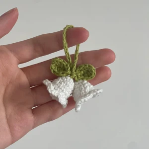 Handgjord nyckelring med virkade blommor - Superfin handgjord nyckelring med vita virkade blommor och gröna blad. Perfekt som en söt accessoar till dina nycklar eller väska. Den är både unik och charmig, och ger en härlig vårkänsla. Passar perfekt som present eller för att piffa upp din egen stil!