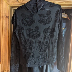 Genomskinlig Svart blommig tröja  - Svart tröja med ett snyggt blommigt mönster. Materialet är mjukt och bekvämt, med långa ärmar som håller dig varm. Storleken är 44, men jag upplever att den är liten i storleken och skulle passa en S. Jag är osäker på materialet, och märket syns inte