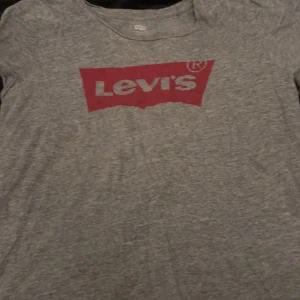 Grå t-shirt från Levi's - Säljer en grå t-shirt från Levi's i storlek M. Den har en klassisk röd Levi's-logga på bröstet och är gjord i mjuk bomull. Perfekt för en avslappnad stil eller vardagsbruk. Passar till allt och är superbekväm!
