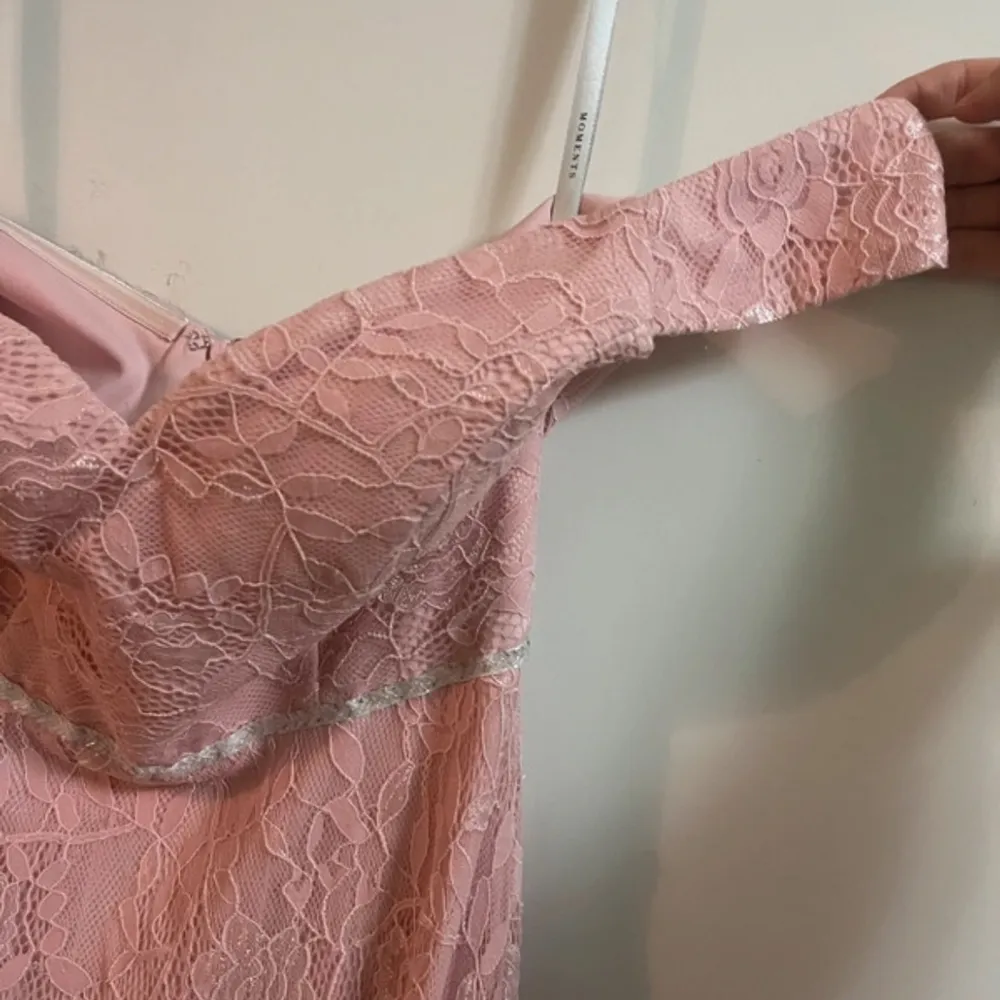 Säljer en superfin rosa långklänning från Moments New York. Klänningen är i spets och har en elegant offshoulder-design. Perfekt för sommarens fester eller en romantisk bal. Den har en dragkedja i ryggen för enkel påklädning. Använd den för att känna dig som en prinsessa! 🌸. Klänningar.