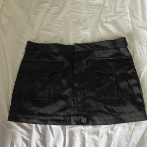 Svart minikjol med cargo design  - Den här svarta minikjolen från Zara är perfekt för dig som vill ha en trendig och mångsidig outfit. Kjolen har en stilren design med praktiska fickor och ett bekvämt snitt. Eftersom den är oanvänd är den i nyskick och redo att bli din nya favorit!