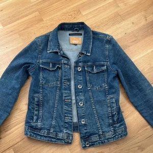 Denimjacka - Här har vi en fin och stilren denimjacka i väldigt bra skick. Den har inga skador och är väldigt bekväm. Den är från ONLY i storleken 36