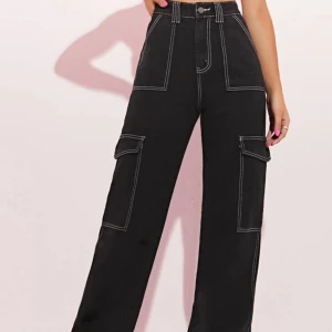 Svarta cargopants med hög midja - Säljer ett par snygga svarta cargopants med hög midja. Byxorna har breda ben och stora fickor på sidorna, vilket ger en cool och praktisk look. Perfekta för både vardag och fest!