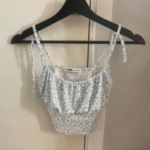 Linne med fjärilar - Sött och somrigt linne från new yorker med ett mönster i blått och vitt. Toppen har smala axelband som knyts och en lätt rynkad detalj framtill. 