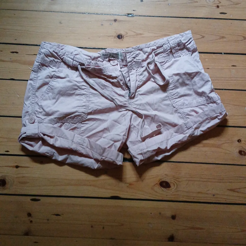 Så sjukt snygga ljusrosa cargo shorts, de går att vika up med hjälp av en knapp så man kan göra de kortare(se bild 3&4) eller så kan man ha dem i normal längd(bild 1&2) midjemått rakt över:44cm, inrebenslängd:10cm(upsatt), 15cm(oupsatt)❤️. Shorts.