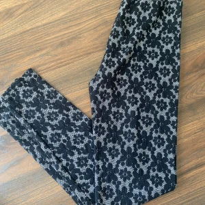 Svarta mönstrade byxor - Säljer ett par svarta byxor med ett snyggt blommigt mönster. Perfekta för både vardag och fest! De är bekväma och stiliga, och passar till många olika outfits.