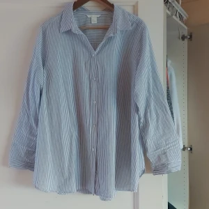 Randig skjorta med knappar - Säljer en stilren och klassisk randig skjorta med knappar. Skjortan har en avslappnad passform och är perfekt för både vardag och jobb. Den har långa ärmar och en krage som ger en tidlös look. Passar bra till jeans eller kostymbyxor!