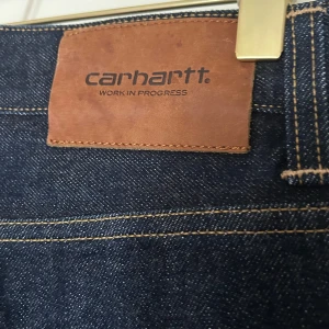 Carhartt Klondike Selveged jeans  - Säljer ett par nya snygga selveged jeans från Carhartt. De har en klassisk femficksdesign med en knappgylf och är gjorda i slitstarkt denim. Perfekta för både vardag och fest!. De har en slimfit passform och är i storlek 28/32. Nyskick utan tecken på användning 