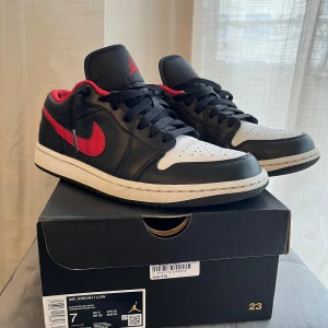 Nike Air Jordan 1 Low i svart och röd - Säljer ett par Nike Air Jordan 1 Low i svart, vit och röd. rätt bra skicka och funkar när som helst och fraktas med box.