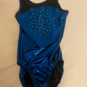 Gymnastikdräkt  - Jättefin gymnastik dräkt med blå metallic/glittrigt tyg och paljetter. Endast använd ett fåtal gånger - skulle säga att den är i nyskick. Säljer då den inte kommer till användning längre 