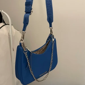 steve madden väska - jättefin blå steve madden väska köpt från zalando för 1000. Knappt använd, nytt skick. Den ska ha en liten väska som ska sitta på bandet, om det önskas så ska jag leta upp den.