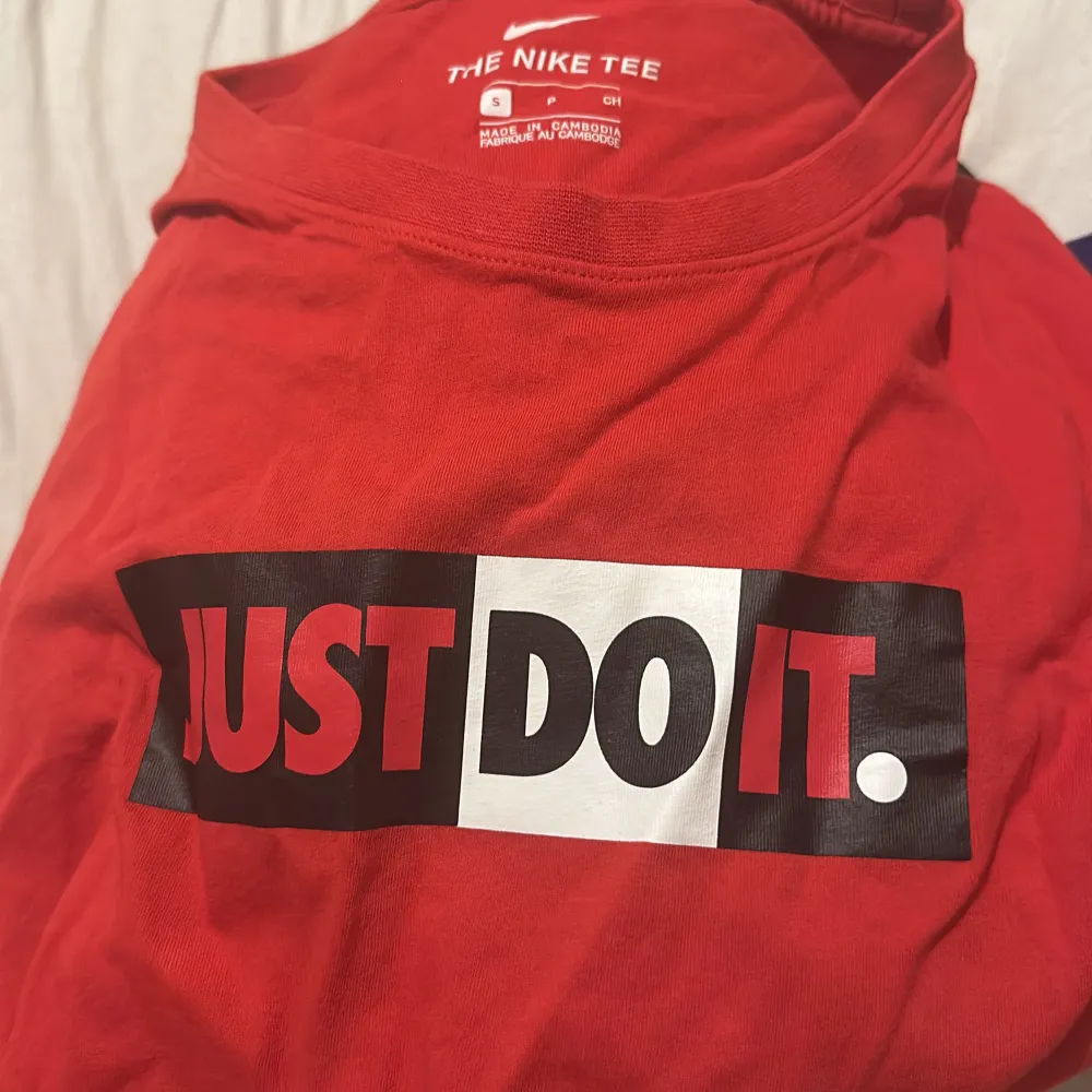 Säljer en röd Nike T-shirt i storlek S med det klassiska 'Just Do It' trycket på framsidan. T-shirten är kortärmad och gjord i mjukt bomullsmaterial, perfekt för vardagsbruk eller träning. Den är i bra skick och redo för en ny ägare!. T-shirts.