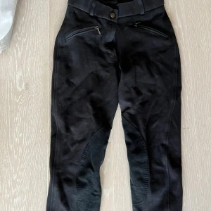 Svarta ridbyxor från Back2Back - Säljer ett par svarta ridbyxor från Back2Back i storlek 34. Byxorna har dragkedjor på fickorna och en knapp i midjan. Det är ej fläckar på, endast lite ludd och hästhår. De är tvättade. 
