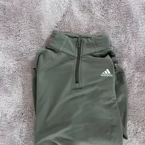 Grön långärmad tränings tröja från adidas med dragkedja vid halsen. Använd fåtal gången och har inga skador eller märken. Storlek S  Färg. Khaki