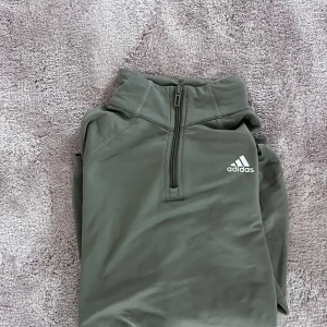 Adidas tröja - Grön långärmad tränings tröja från adidas med dragkedja vid halsen. Använd fåtal gången och har inga skador eller märken. Storlek S  Färg. Khaki