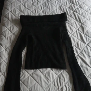 Svart ribbad offshoulder-tröja - Säljer en snygg svart ribbad offshoulder-tröja. Perfekt för höst och vinter med sin mysiga och stilrena design. Tröjan har långa ärmar och en bred krage som ger en elegant look. Passar både till vardags och fest! Kan sänka pris vid snabb affär💕