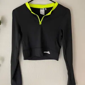 Säljer en oanvänd mörkgrå långärmad träningstopp från Adidas Stellasport med neongula detaljer. Den har en dragkedja framtill och är croppad för en modern look. Perfekt för träning eller en sportig vardagsstil.