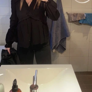Blus nakd  - svart strukturerad volangblus från NAKD, bra skick. den är i storlek 34 men passar en 36 också då den har en oversized passform. jag har satt en säkerhetsnål på första bilden men på andra bilden ser man tydligare hur v-ringad den egentligen är !! 💝🎀