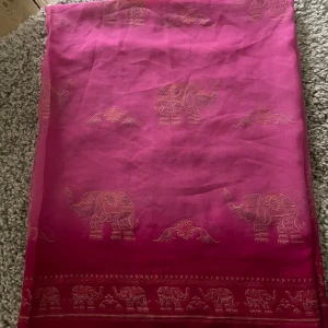 Rosa klänning med elefantmönster - Säljer en superfin rosa typ schal med ett unikt elefantmönster. Den är perfekt för sommardagar och har en luftig och bekväm passform. Schalen är i ett lätt material som känns skönt mot huden.