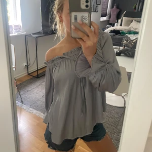 Siden blus - Säljer denna fina siden blus i en unik silverblå färg! Den har knyte och är off shoulders💗inga defekter alls!