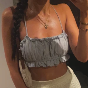 Ljusblå croppad linnetopp - Säljer en superfin ljusblå croppad linnetopp med smala axelband. Toppen har en söt volangdetalj längst ner och är perfekt för sommardagar. Även på baksidan är det jättefin detalj med snören, Den är både bekväm och stilren.