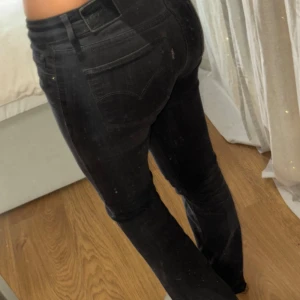 Low waist bootcut levi’s jeans - Low waist bootcut jeans från Levi’s. På bilderna ser de lite gråa ut men de är svarta med en liten ton av grå. Längst ner är de ihopsydda (kolla bilderna). Passar korta personer/personer med korta ben. Lågmidjad. Fråga gärna frågor