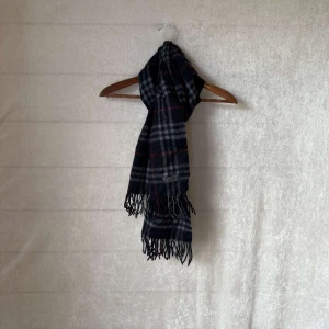 Burberry halsduk - Säljer en klassisk rutig halsduk från Burberry i mörkblätt, grått och rött. Den är gjord av 100% mjuk kashmir. Perfekt för att hålla sig varm och stilren under kyliga dagar. Passar både höst och vinter! Skick9/10 Vid frågor är det bara att skriva👍