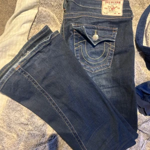 True religion Jeans - Ett par true religion jeans som har använts men inte överdrivet mycket, bra skick, säljer dessa för dom är för stora. Storlek 30 i midjan och 34 i längden, för långa på  mig så därför finns de en liten skavank på byxan längst ner , low rise bootcut 