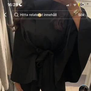 Svart poncho med knytband - Säljer en elegant svart ponchojacka från missay med knytband i midjan. Perfekt för höst och vår, den har en stilren design med en knappdetalj vid halsen. Jackan är i nyskick och passar både till vardags och festliga tillfällen. 