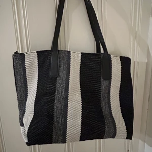 SHEIN - Randig tygväska i svart,vit & grå - Väska är en randig mönstrad tygväska i från SHEIN men dragkedja!  Färg: Svart,vit och grå  Axelbandet är i svart  Väskan är oanvänd därför i ett fint skick💞