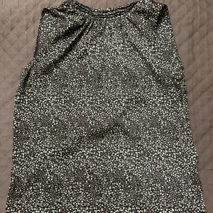 Blommig blus - Säljer denna åt min mamma. Blommig blus utan ärm. Storlek S, normal i storleken. Tunt material. Använd fåtal gånger. 