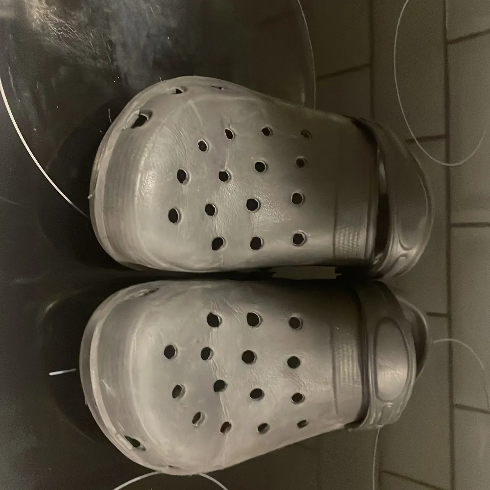 Säljer ett par svarta Crocs i storlek 38. De är i välanvänt skick men fortfarande bekväma och perfekta för sommarens alla äventyr. Ventilerande hål och justerbar hälrem för extra komfort. Perfekta för både inomhus och utomhusbruk!. Skor.