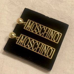 Stora Moschino örhängen i Guld  - Snygga maffiga guld örhängen från Moschino i fint använt skick  Haft dem några gång på mig men de finns inte något fel eller tappat guld Köpta för ganska länge sedan  Inte min stil riktigt så därför säljer jag dem nu 