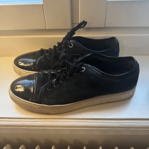 Lanvin  - Snygga blå/gröna Lanvin sneakers med glansig tå och snörning. Skorna har en vit sula som ger en cool kontrast. Perfekta för en stilren look. Storlek 43