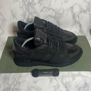 Svarta sneakers från Valentino - Snygga svarta sneakers storlek 39.5 men passar 40från Valentino med ikoniska nitar på hälen. Skorna är tillverkade i en kombination av skinn och mocka, vilket ger en lyxig känsla. Perfekta för dig som vill ha en stilren look med en twist.