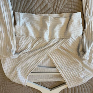 Beige ribbad omlottopp - Snygg beige omlottopp med ribbad struktur och långa ärmar. Perfekt för en stilren look.