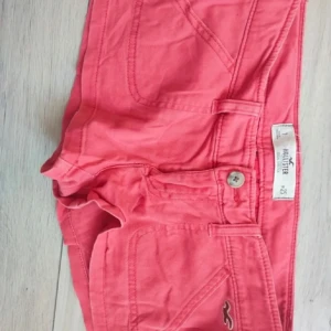Rosa shorts från Hollister - Snygga rosa shorts från Hollister med klassisk femficksdesign och knappgylf. Perfekta för varma sommardagar. De har en lågmidjad passform och är tillverkade i ett bekvämt bomullsmaterial.