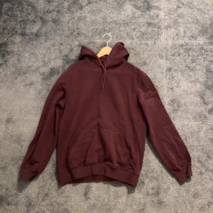 Vinröd - Säljer en stilren vinröd hoodie med justerbar huva. Perfekt för en avslappnad look.