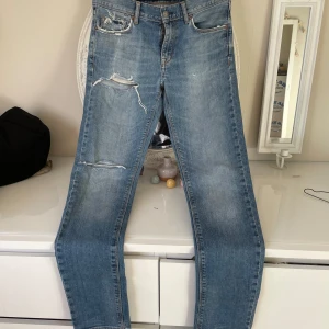 Blå jeans från J.Lindeberg - Snygga blå jeans från J.Lindeberg med slitna detaljer på framsidan. De har en klassisk femficksdesign och en bekväm passform. Perfekta för en avslappnad stil.måttet på midjan är 42cm och måttet på innersida är längd 82cm , och sidor på ben längd är 1,06 m. Har kostat 1300kr