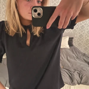 Mörkblå blus med volangärmar - Säljer en stilren svart blus med korta volangärmar och en liten öppning vid halsen. Perfekt för en elegant look. Blusen har en normal passform och är tillverkad i ett mjukt material.