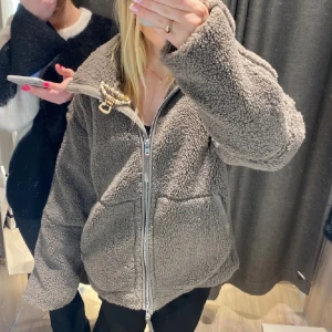 Brun teddyjacka med dragkedja - Mysig brun teddyjacka med dragkedja framtill och hög krage. Perfekt för våren. Säljs inte längre. Den har 2/3 sömmar som gått upp men som är enkla att sy fast och inget man ser men annars är den är i bra skick i storlek XS men sitter som S. 