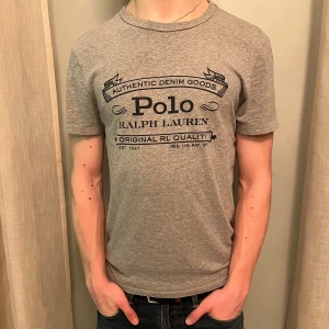Ralph Lauren T-Shirt - Säljer en grå t-shirt från Ralph Lauren med tryck på framsidan. Super bra skick: Han på bilden är 177cm och väger 67Kg. Skriv vid minsta fundering👍