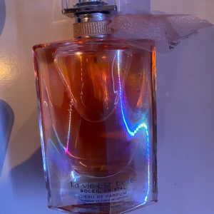La Vie Est Belle Soleil Cristal Eau de Parfum - Säljer en elegant flaska av La Vie Est Belle Soleil Cristal Eau de Parfum från Lancôme. Flaskan har en vacker, skimrande design med en ljus orange nyans. Perfekt för den som älskar en lyxig och strålande doftupplevelse. Parfymen är helt oanvänd, dock finns inte kartongen kvar! 🧡💗