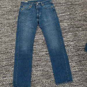 Blå jeansbyxor från Levi's - Klassiska blå 501 jeans från Levi's i gott skick med mindre slitningar 