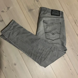 Grå jeans från Replay - Snygga grå jeans från Replay i modellen Anbass. De har en slim fit passform och är tillverkade i ett bekvämt material. Perfekta för en stilren look med klassiska femfickorsdesign och dragkedja. De är i fint skick. W31 L30