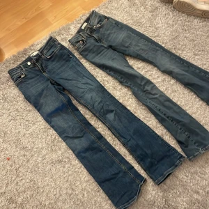 Två par blå jeans - Två par blå jeans i olika nyanser. Det ena paret har en bootcut-stil medan det andra är mer skinny. Båda har klassisk femficksdesign och knappgylf. Perfekta för en avslappnad look.