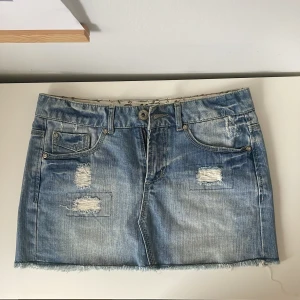 Lågmidjad jeanskjol med slitningar - Ljusblå lågmidjade jeanskjol. Slitningar och jättecoola detaljer