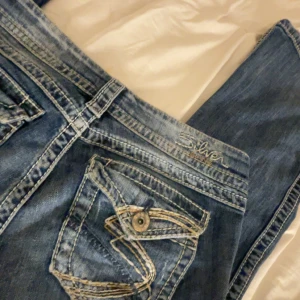 Blå jeans från Silver - Snygga blå jeans av märket Silver jeans med slitna detaljer och en klassisk sliten design. Jeansen har snyggt detaljerade bakfickor. Perfekta för en avslappnad stil. Passar mig är 173💖de är väldigt stretchiga så passar nog en 34-36 men även en liten 38